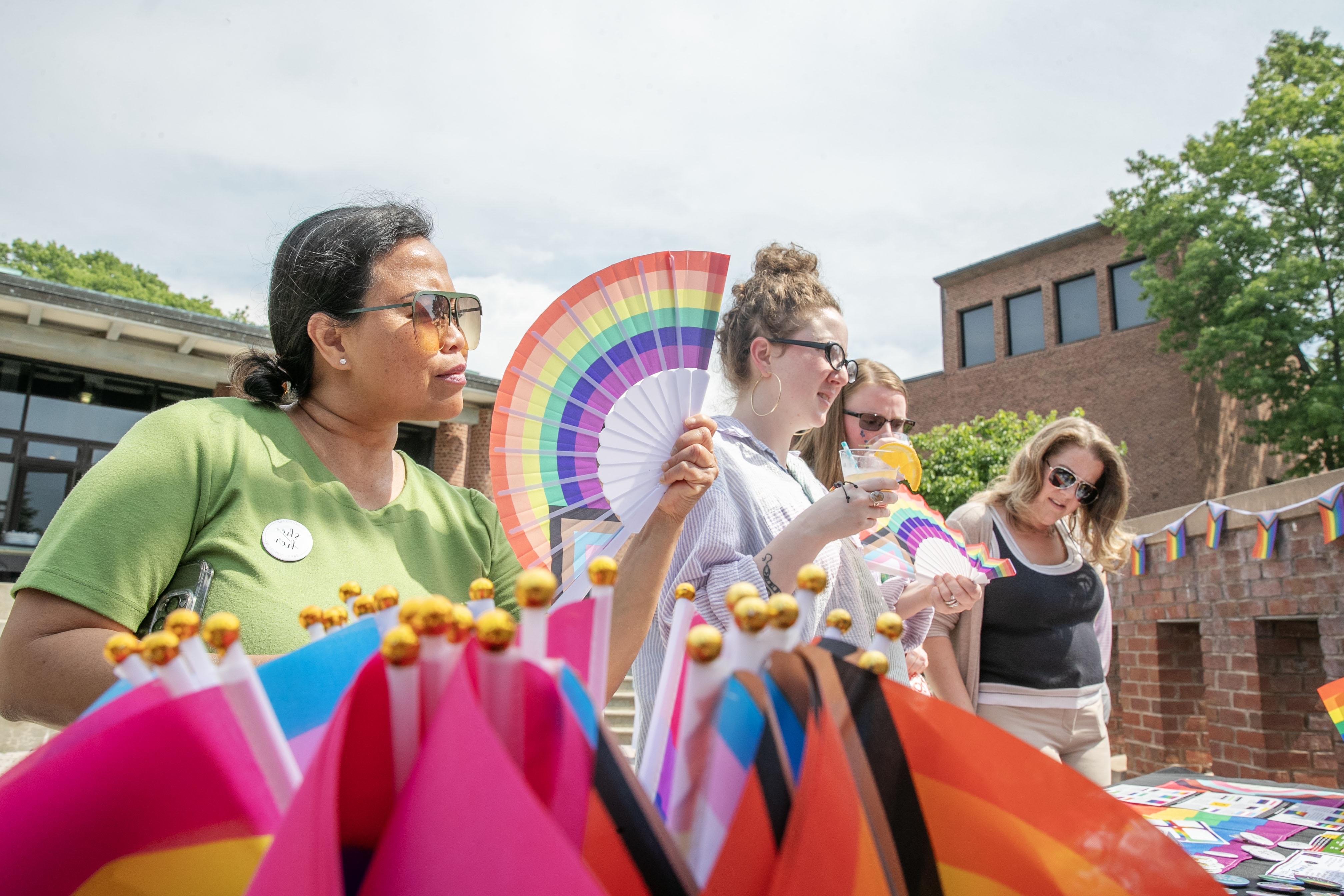 Attendees using Pride-themed fans to keep cool